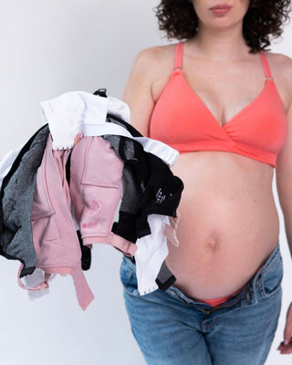 Best bras for pregnancy — Feelou maternity bra worn during pregnancy, holding a pile of bras you no longer need